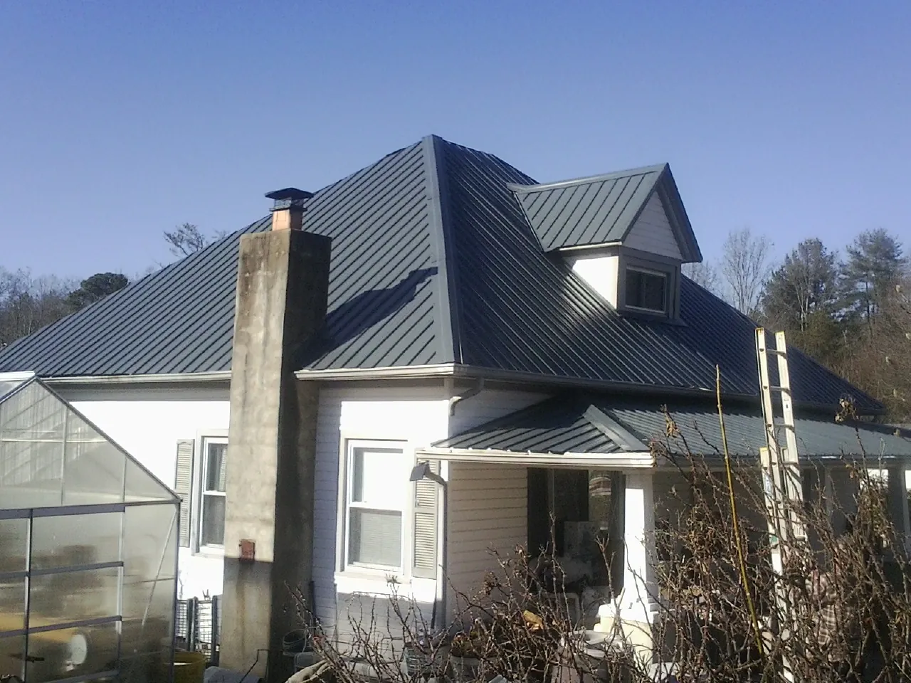 Dark blue standing seam metal roof on a white farmhouse with dormer — Slate & Tile Roof Repair by Roofing Brothers in Rowlesburg