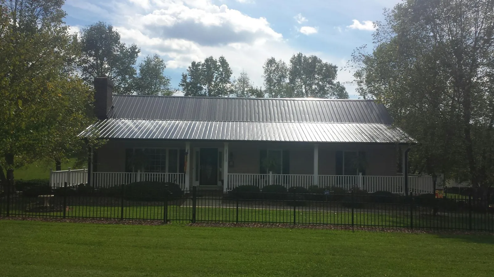Gray metal roof on a brick ranch with a full width front porch — Gutter Guard Installation work by our crew in Rowlesburg
