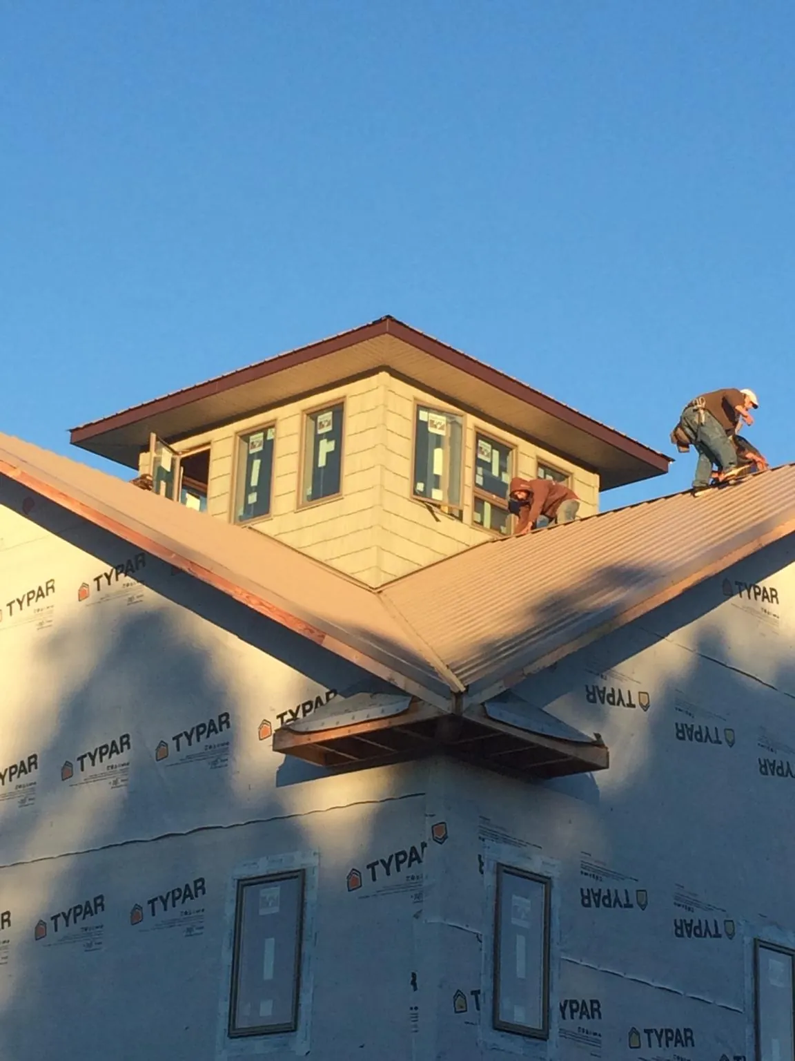 Roofers working around a rooftop cupola on a new metal roof at sunset — Roof Waterproofing in Rowlesburg by Roofing Brothers